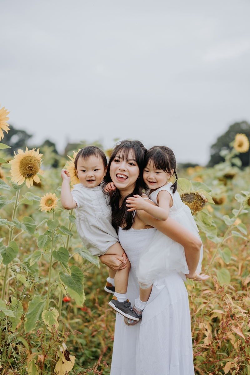 Mother and her two young children laughing in a sunflower field-Didsbury Family Photographer